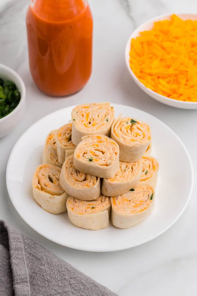 Buffalo Chicken Pinwheels stacked on a white serving plate.