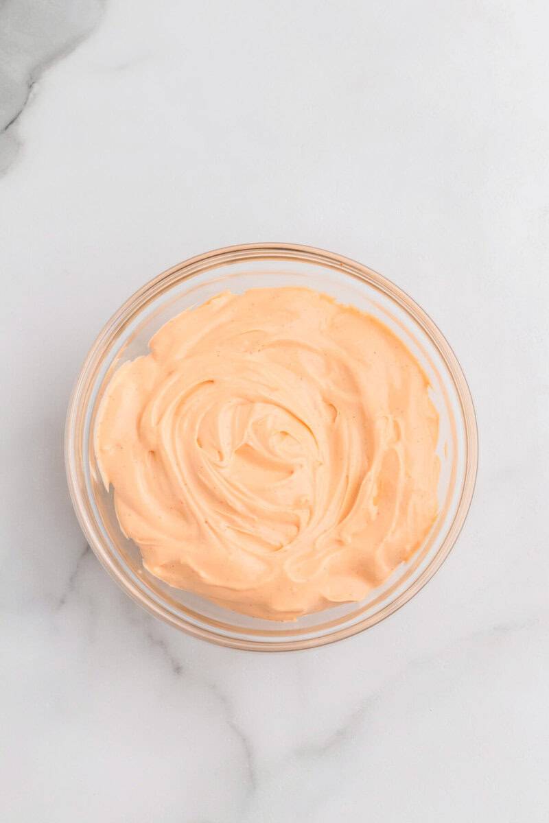 mixing the cream cheese and buffalo sauce together in a glass bowl.