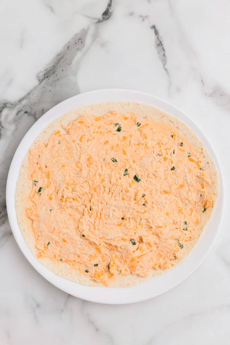 buffalo cheese mixture spread across a tortilla.
