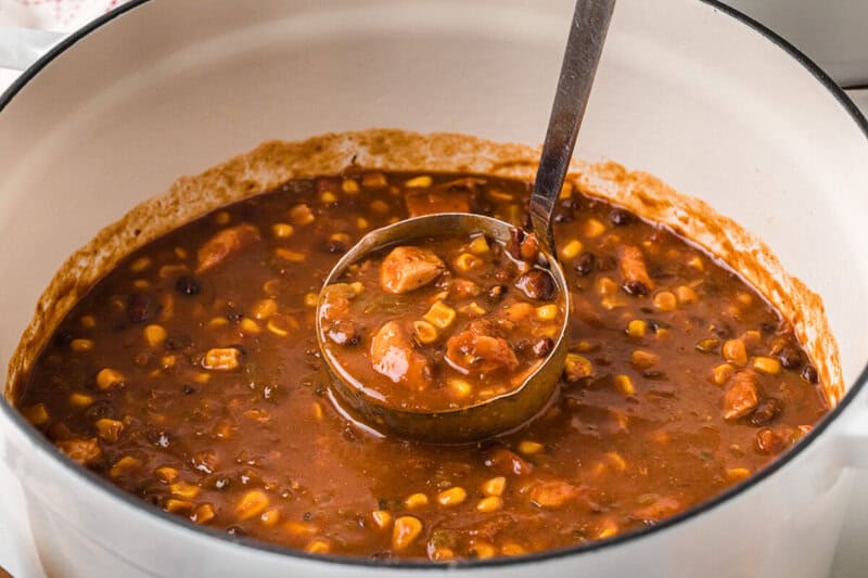 serving the chicken taco soup out of the pot with a ladle.