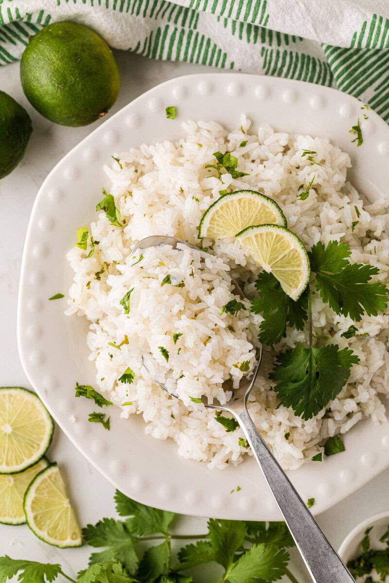 scooping the Cilantro Lime Rice with a spoon off the white plate.