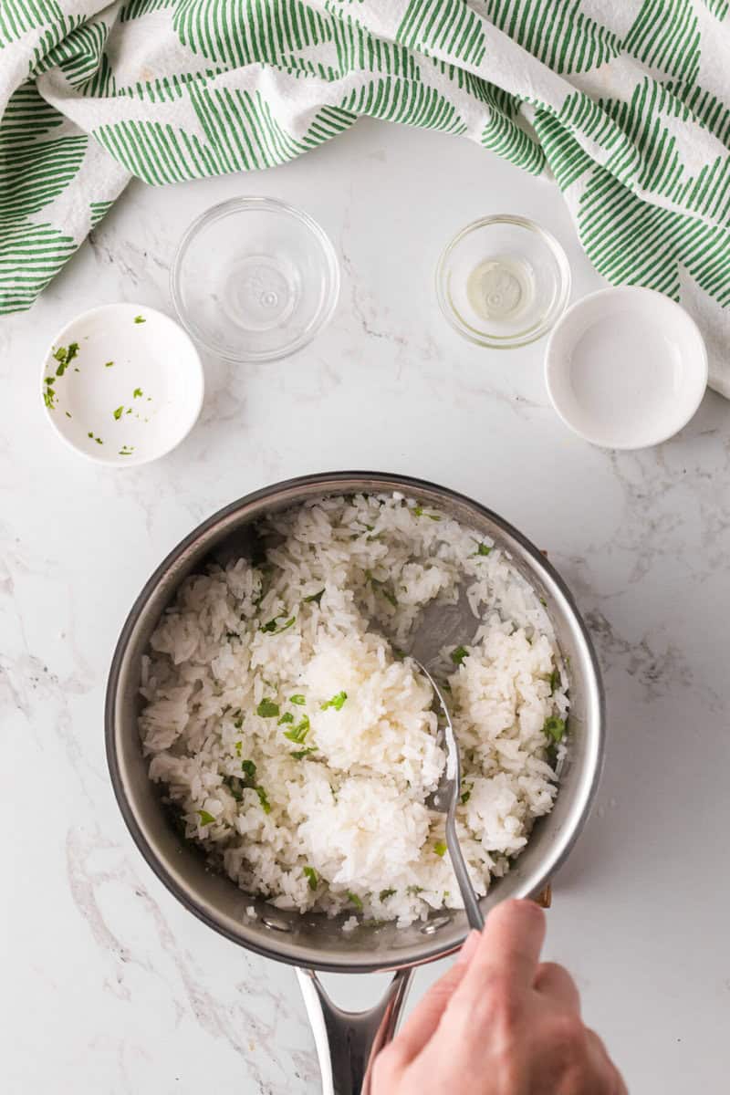 stirring in the ingredients with the rice to make the Cilantro Lime Rice.