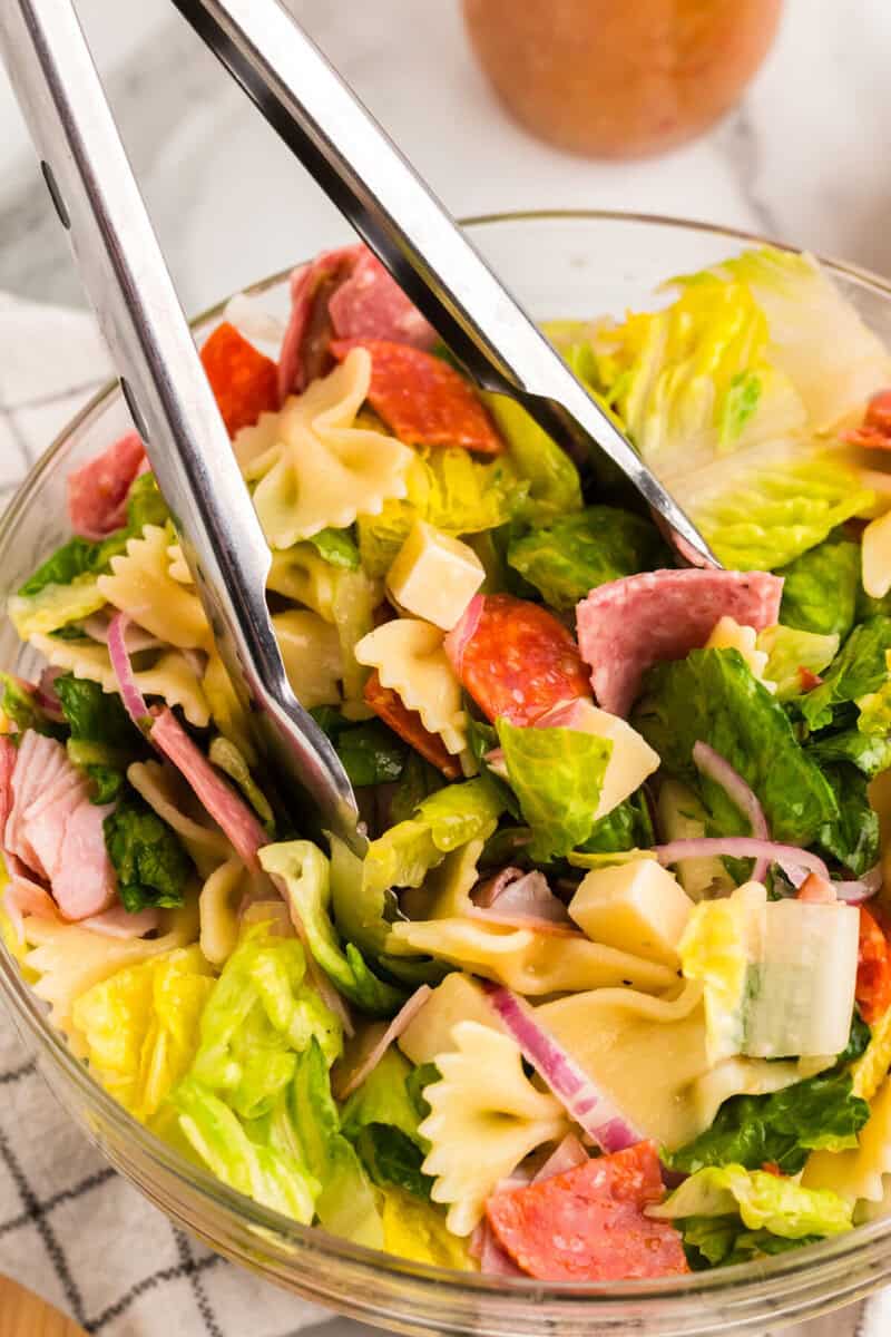 tossing the salad with tongs.