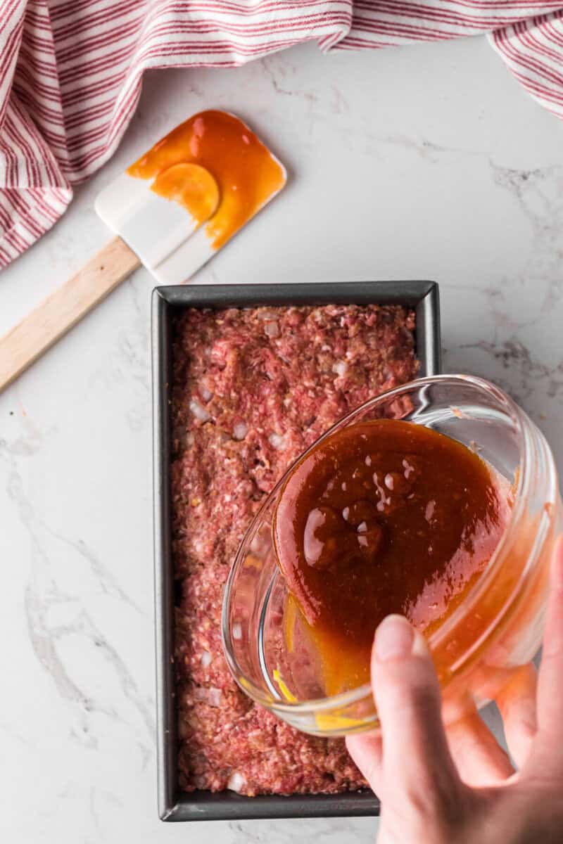 pouring the sauce on top of the meatloaf.