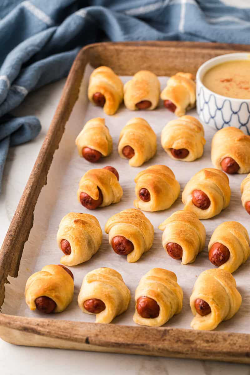 Pigs in a Blanket served on a wooden tray with the Honey Mustard dipping sauce.