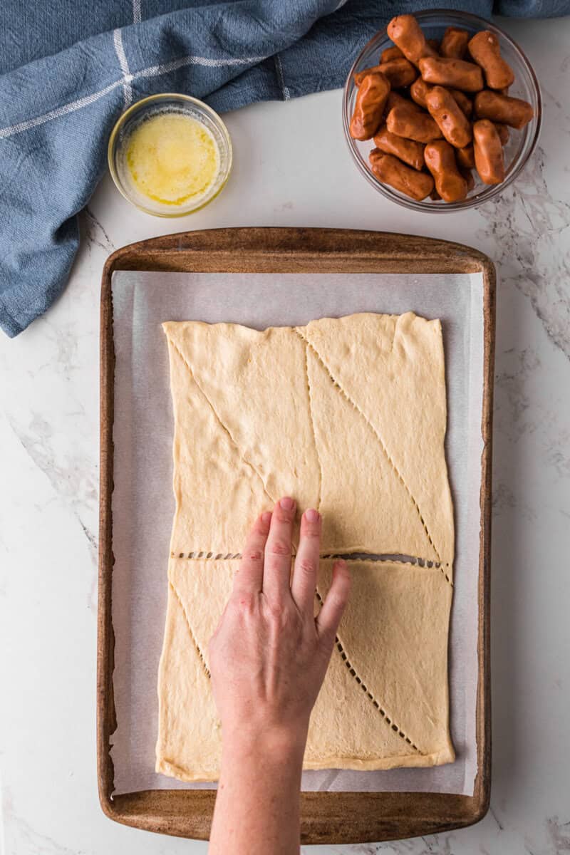 rolling out the crescent roll dough on the baking sheet.