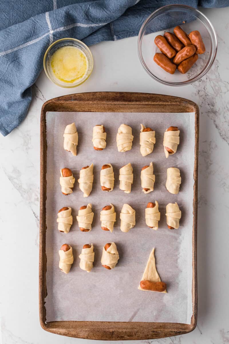 rolling a cocktail weenie in the crescent dough.