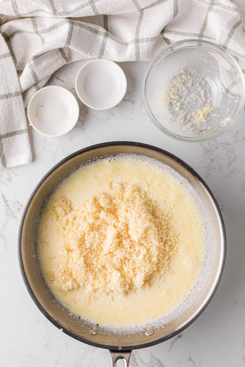 adding the parmesan cheese to the sauce.