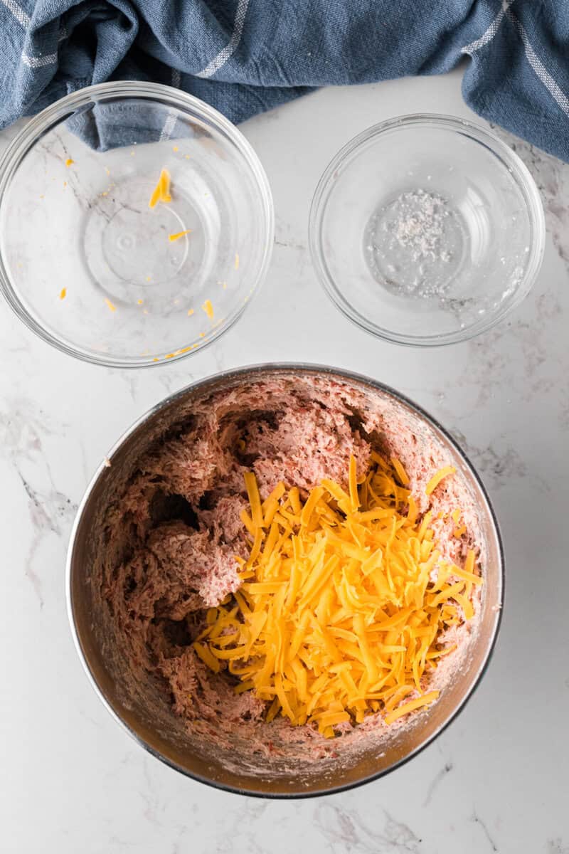 adding the cheese to the sausage ball mixture.