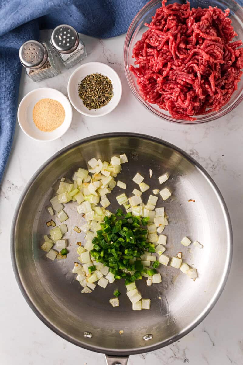cooking the onions and jalapenos in a skillet.