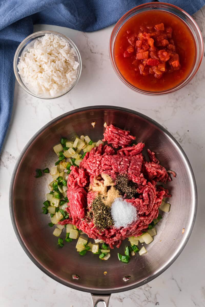 adding the ground beef and seasoning to the onions and jalapenos.
