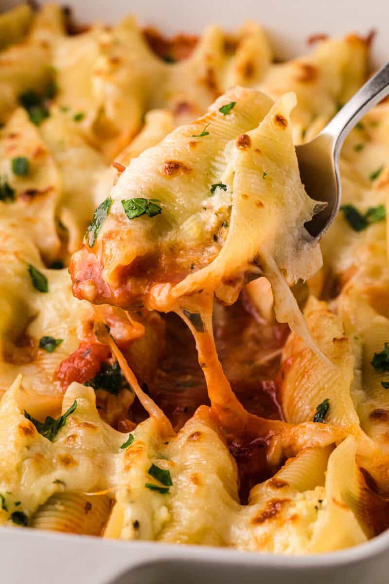 closeup of the Stuffed Shells being served with a metal spoon.