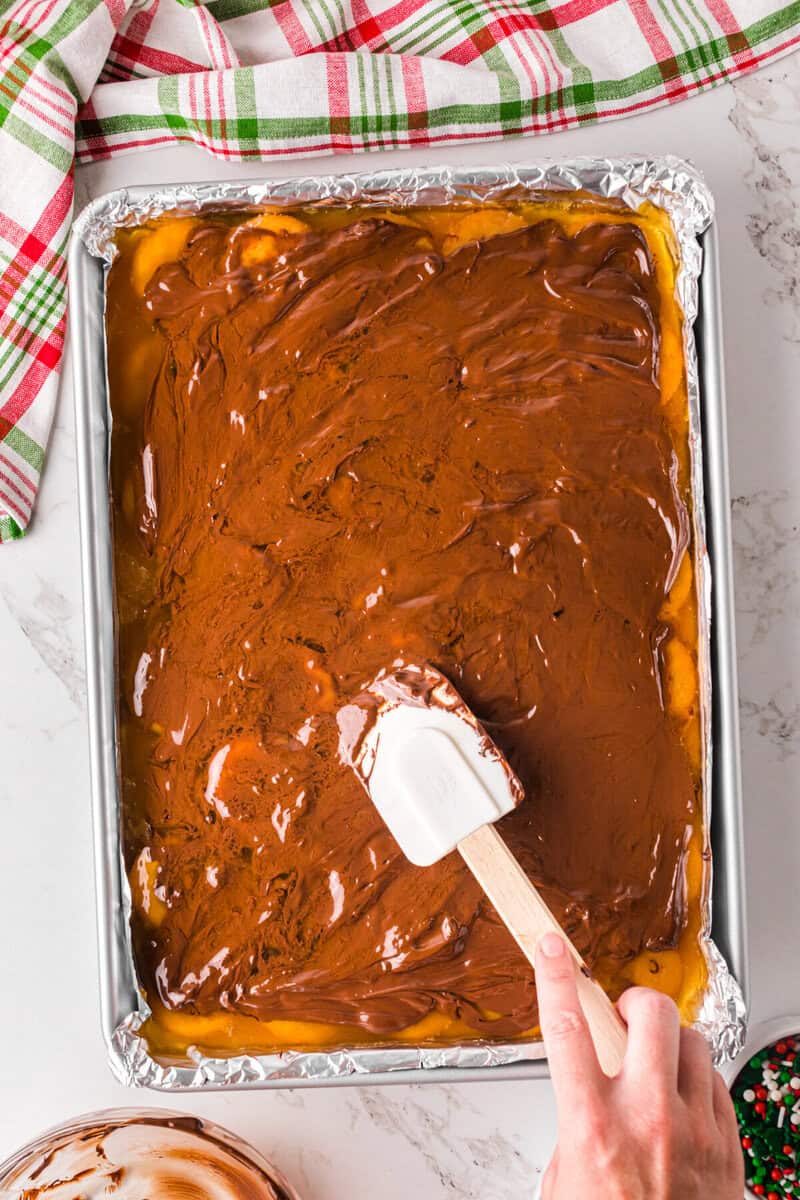 spreading the melted chocolate chips over the Ritz Crackers.