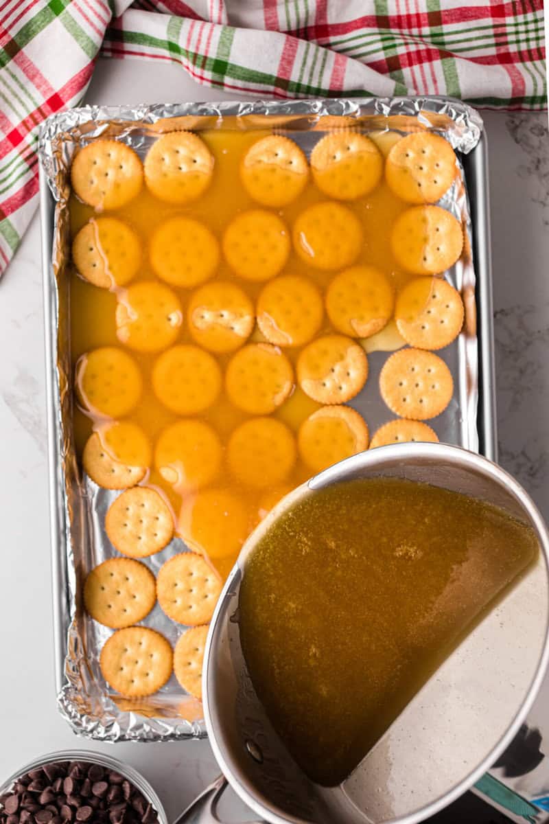 pouring the melted butter and sugar over the Ritz Crackers.