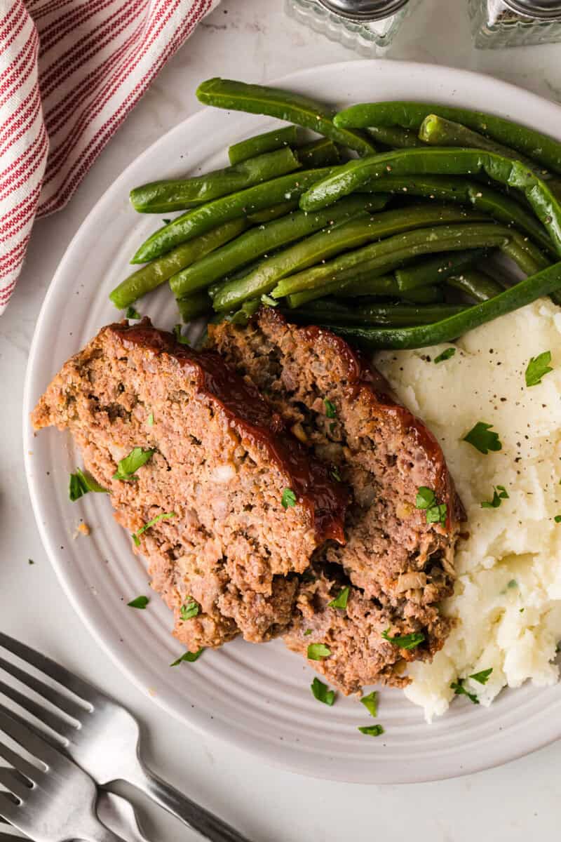 meatloaf, green beans and mashed potatoes served on a plate.