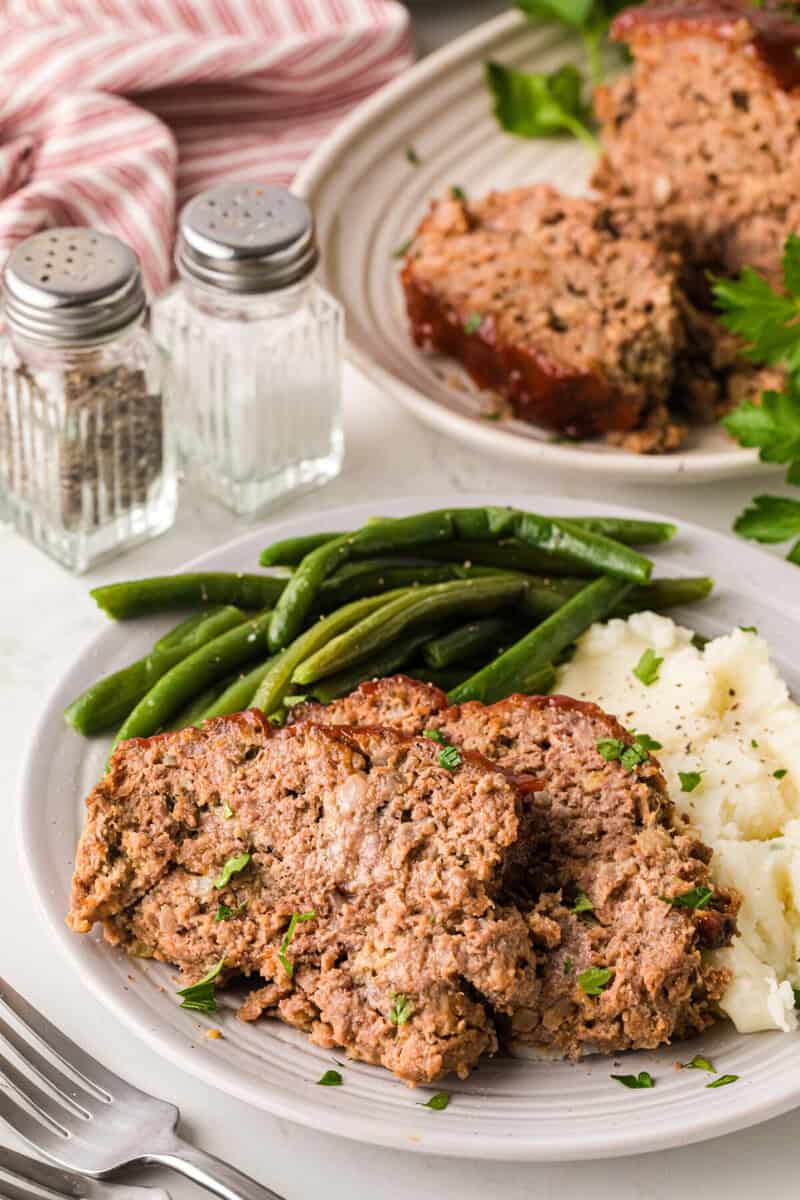 dinner plate served with meatloaf, green beans and mashed potatoes.