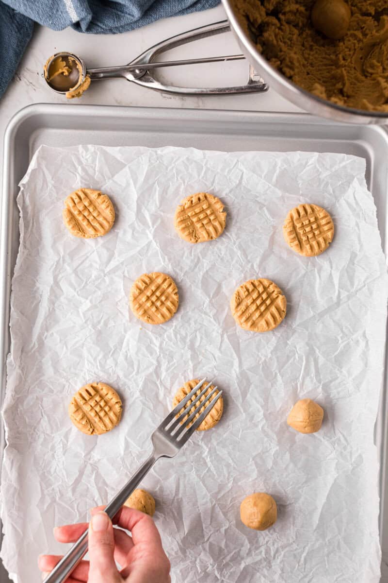 using a fork to press the peanut butter cookie balls.