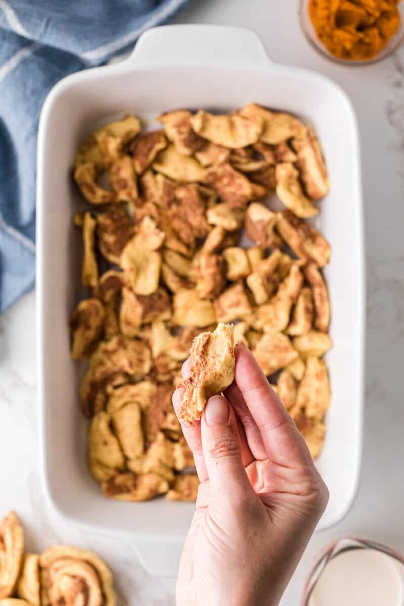 putting the cinnamon roll pieces into the bottom of the casserole dish.