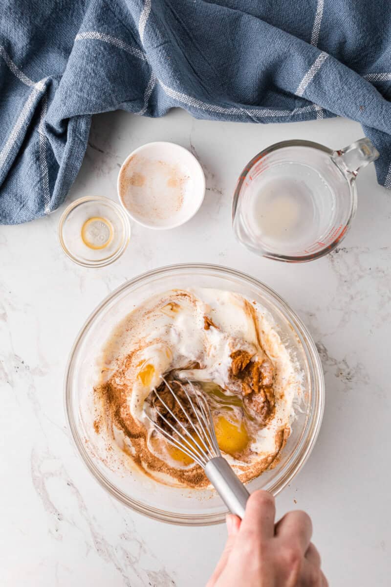 mixing together the eggs, cream, seasoning and pumpkin together in a glass bowl.