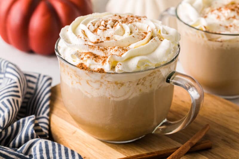 closeup of the Pumpkin Spice Latte in a glass mug on a wooden serving board.