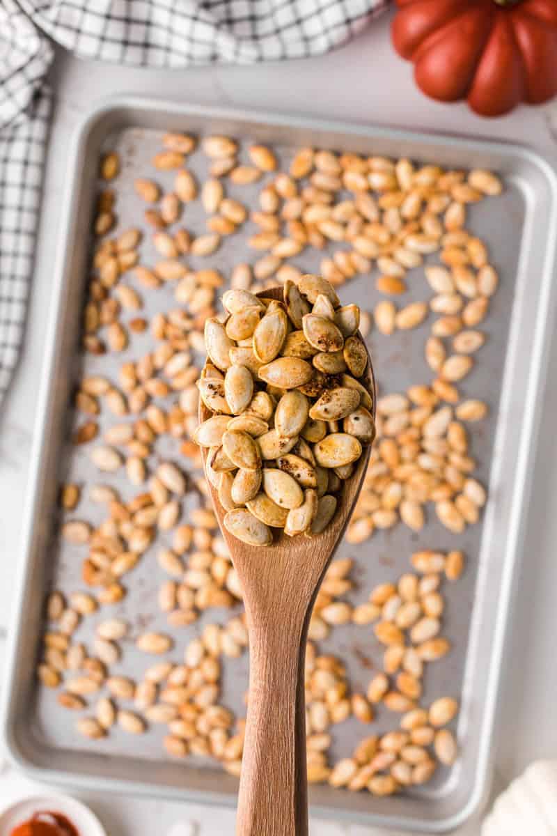 closeup of the pumpkin seeds scooped on the wooden spoon.