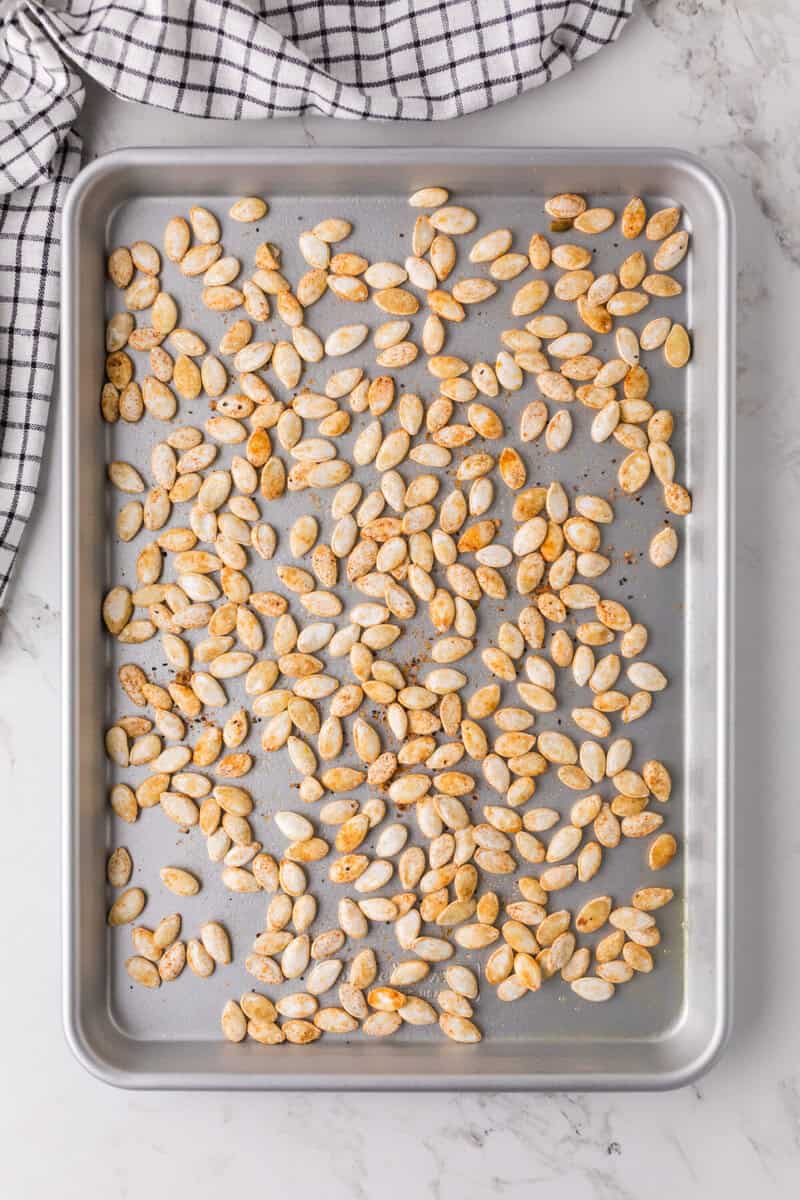 pumpkin seeds spread out on the baking sheet.