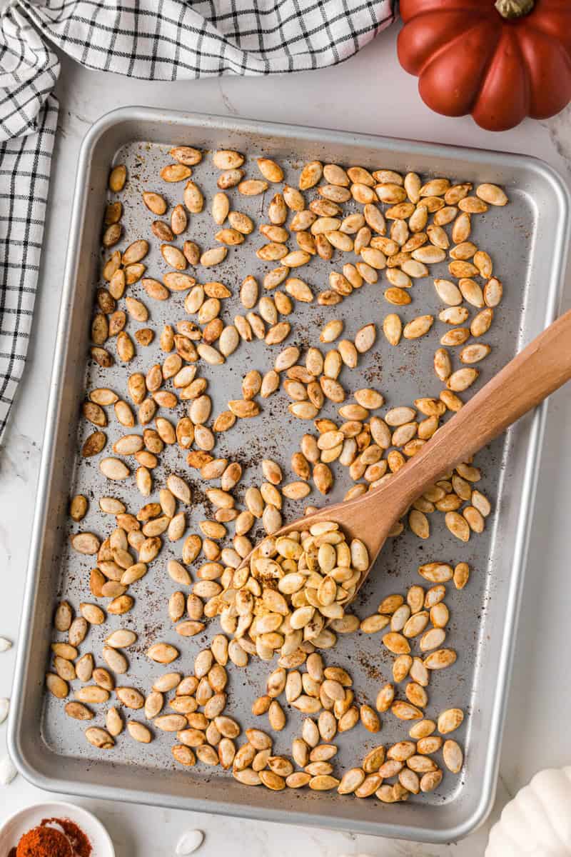 scooping the pumpkin seeds with a wooden spoon.