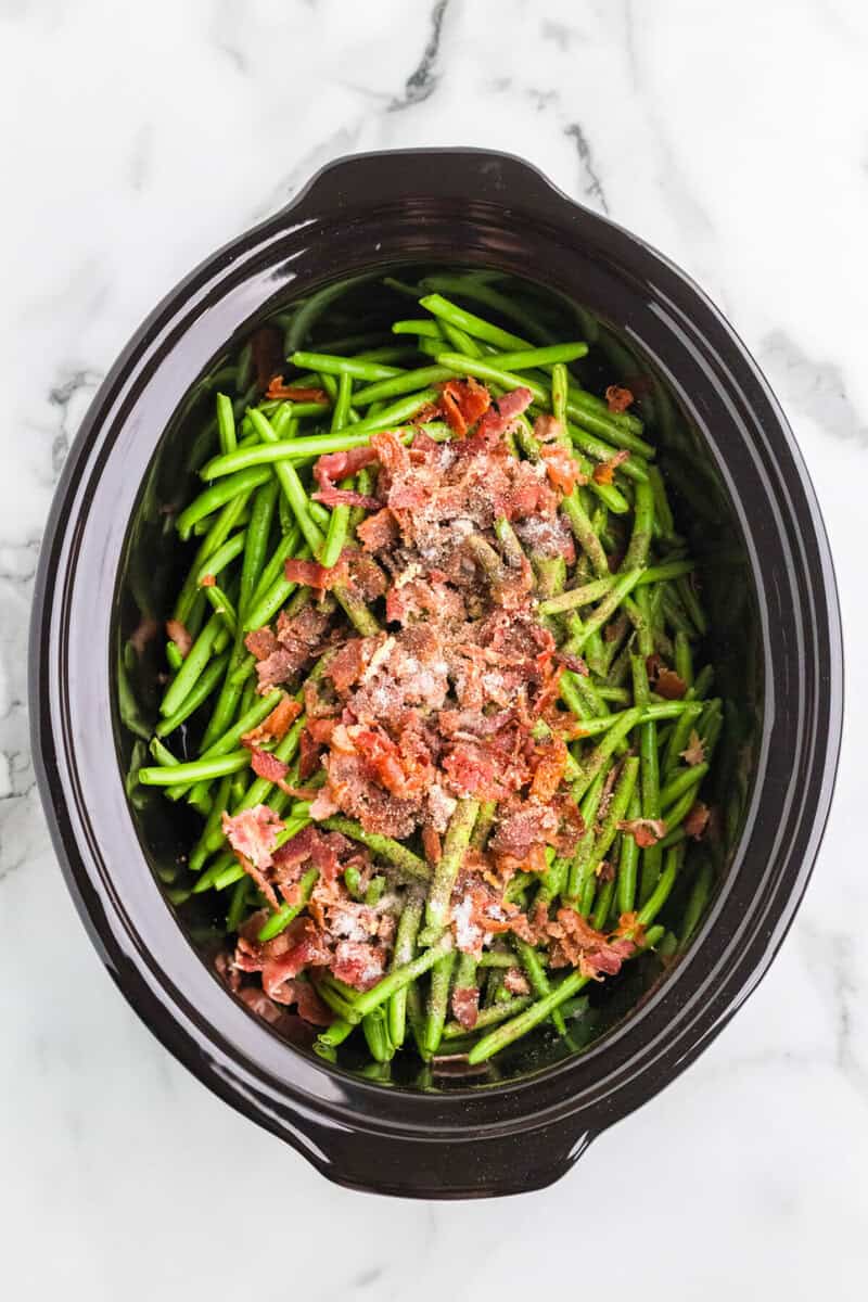 top-down view of the green beans and bacon in the slow cooker.