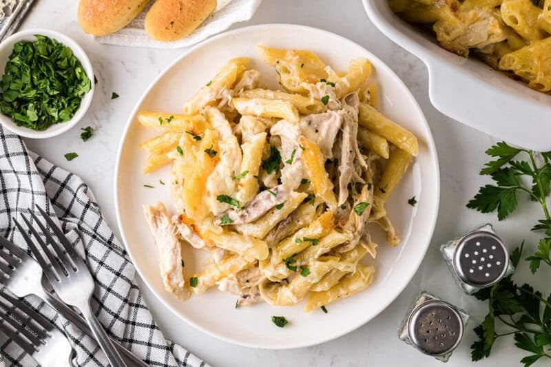 chicken alfredo casserole bake served on a white plate with creamy penne and shredded chicken