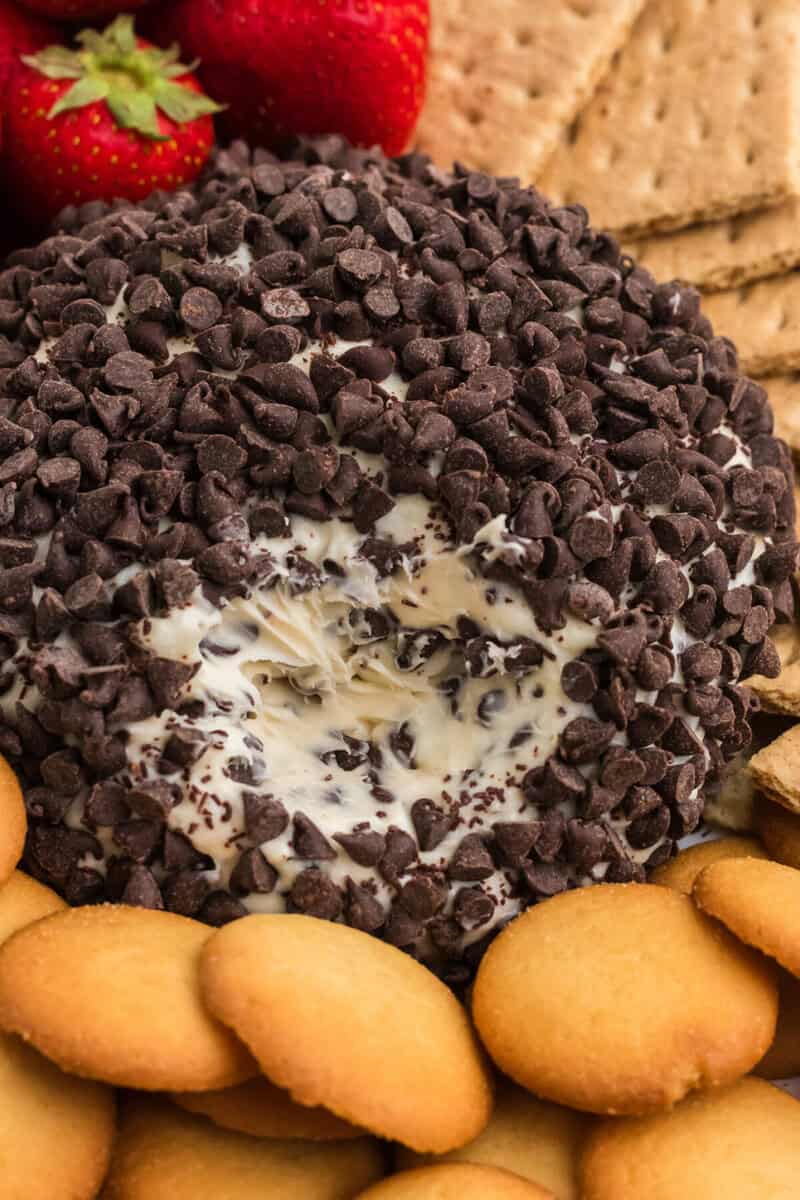 closeup of the cheese ball with a piece taken out of it.