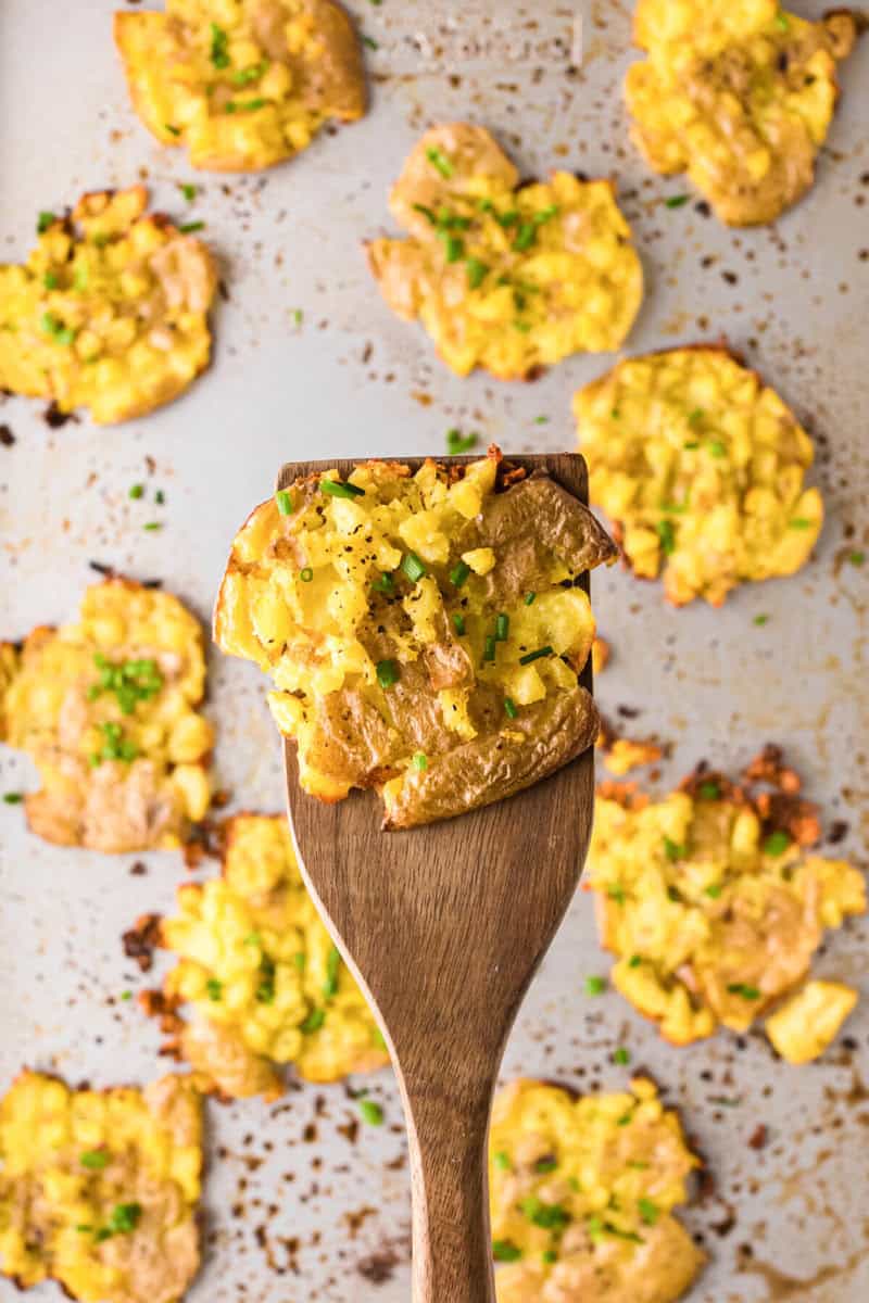 serving the smashed potatoes with a wooden spatula.