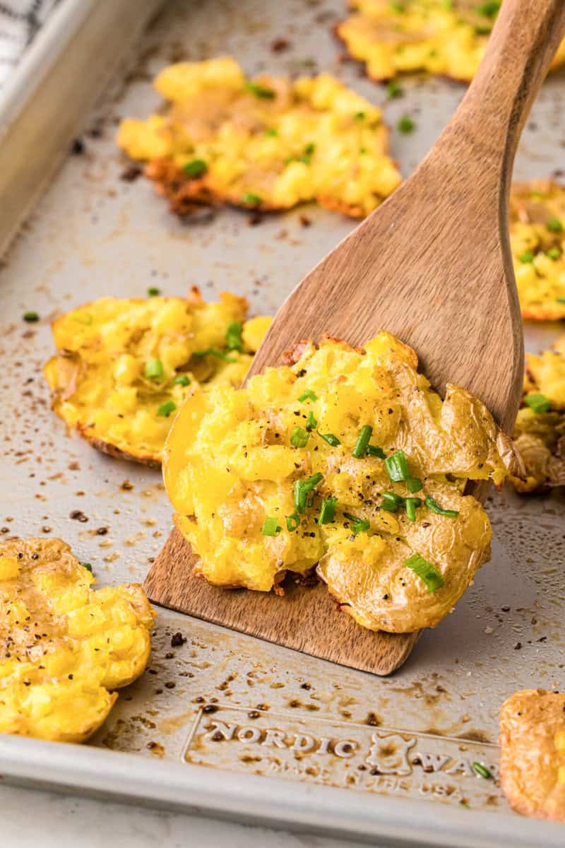 serving a smashed potato with a wooden spatula.