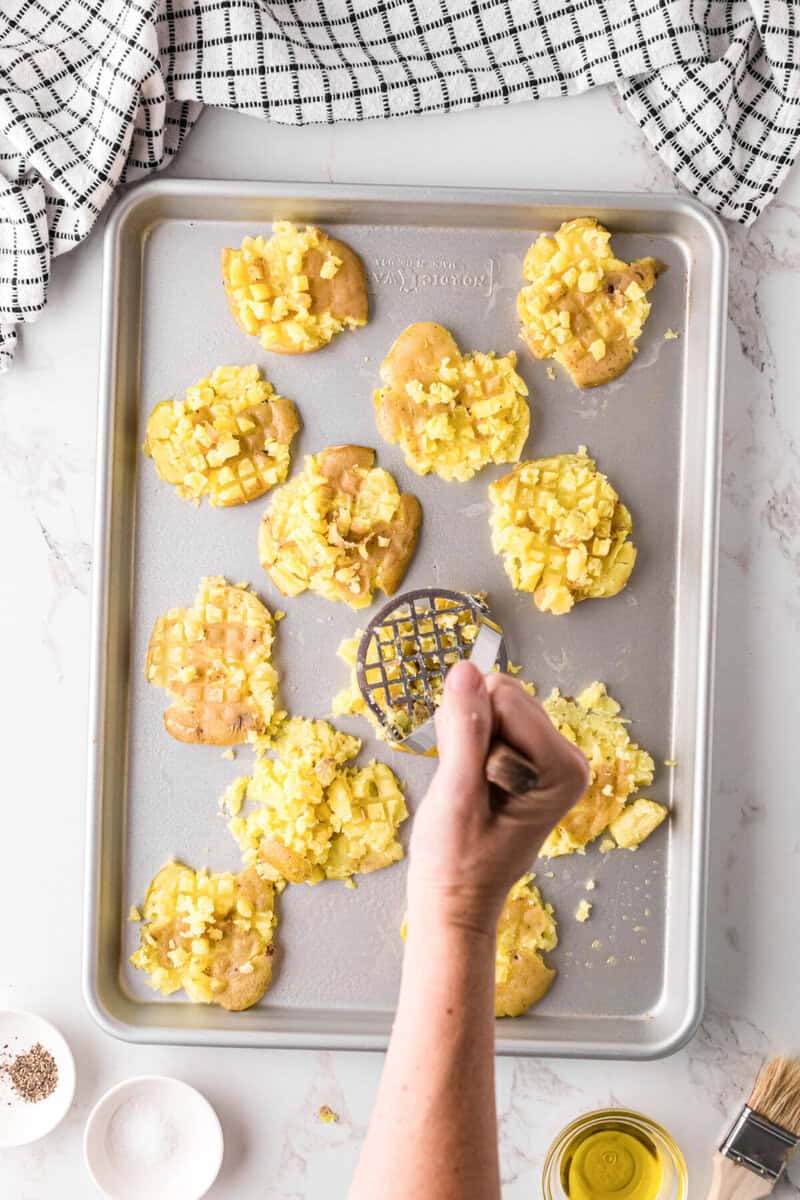 using a potato masher to smash the potatoes.