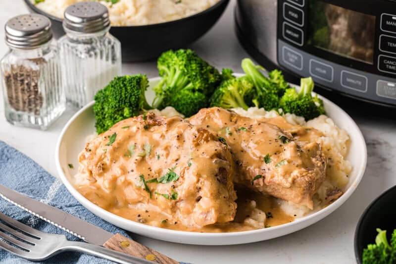 Slow Cooker Smothered Pork Chops served on a white plate with broccoli.