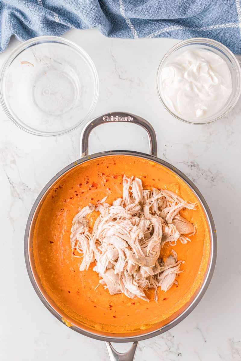 adding the chicken to the buffalo sauce dip.