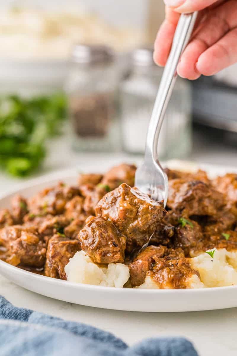 closeup of the Slow Cooker Beef Tips served on a white plate with mashed potatoes.