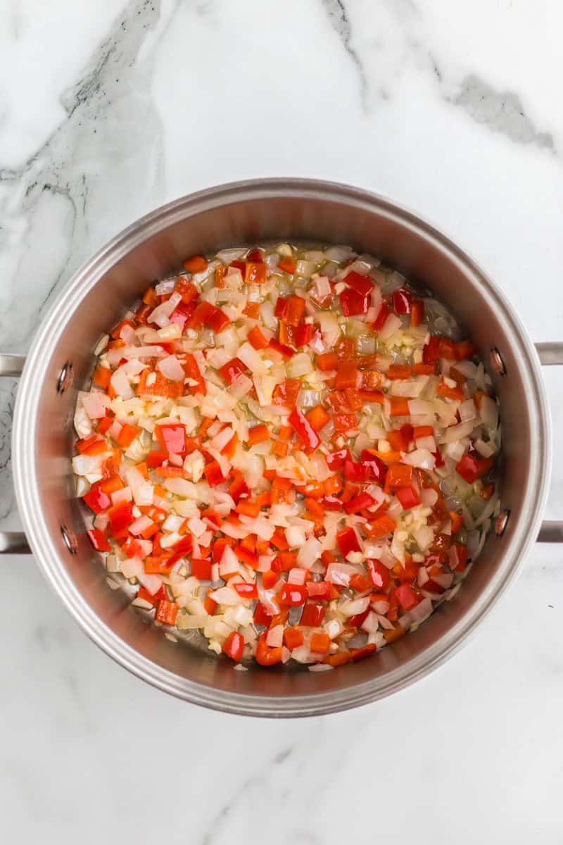 cooking the onions and peppers together in a large pan.