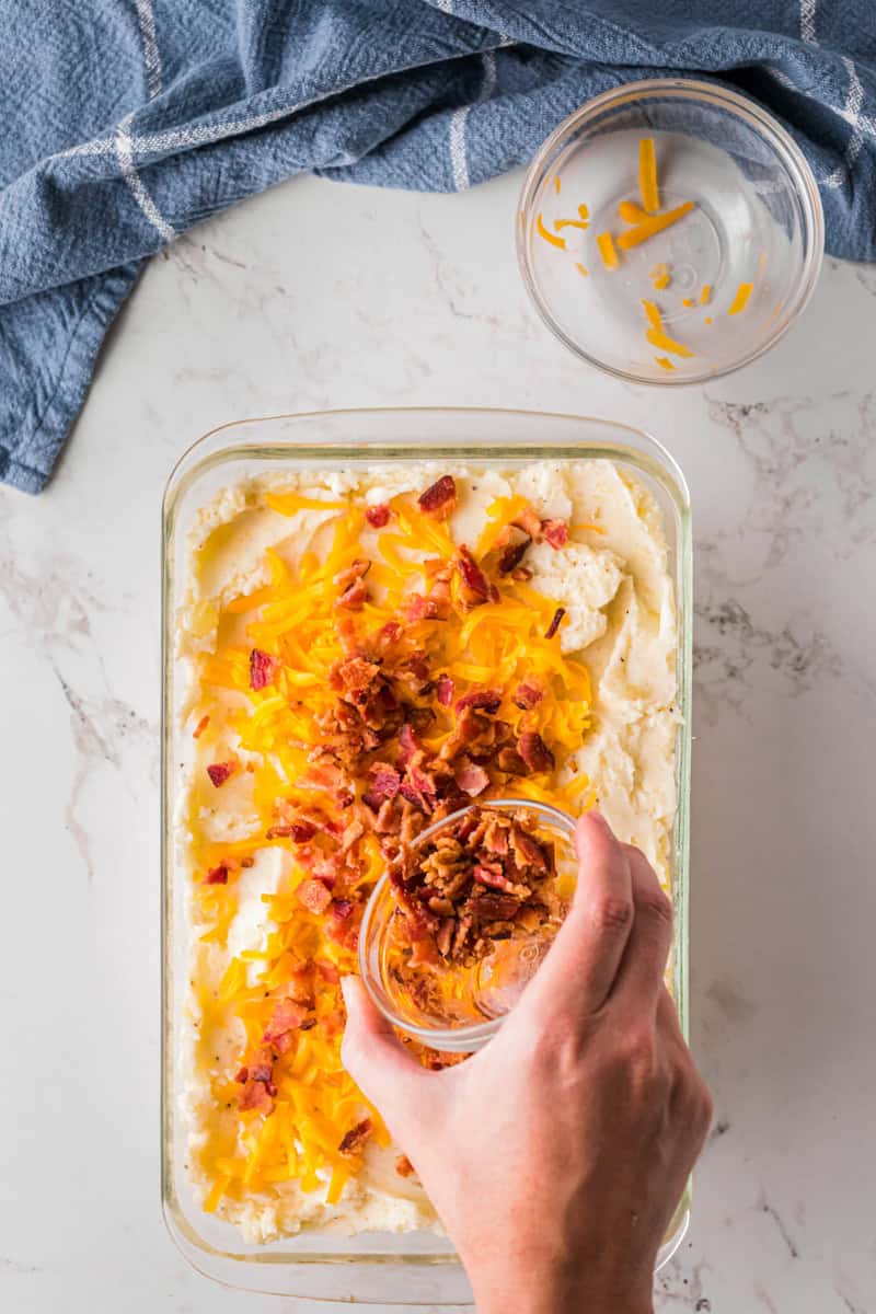 topping the mashed potatoes with cheese and bacon.