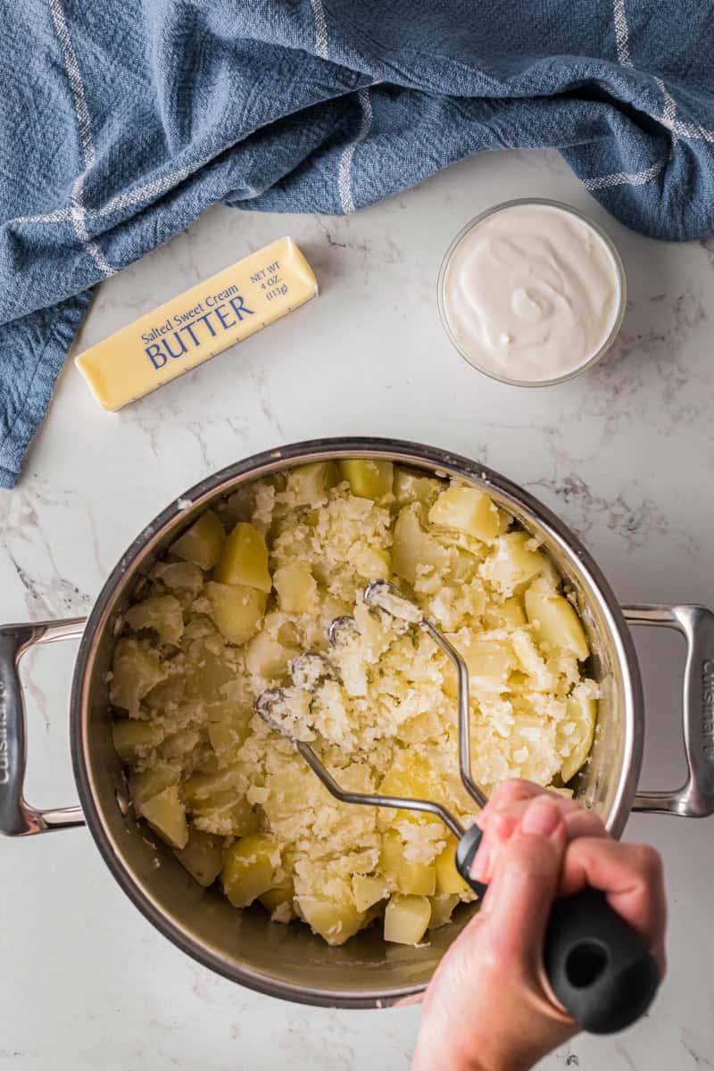 mashing the potatoes in the large pot.
