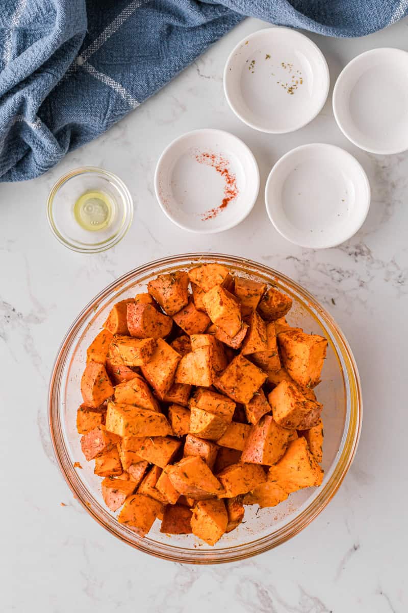 mixing the roasted sweet potatoes with the oil and seasoning.