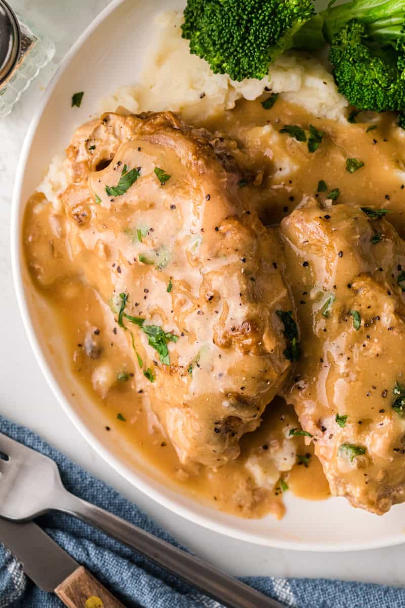 top-down view of the smothered pork chops served on a white plate.