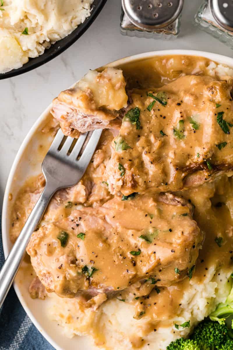 using a fork to eat the pork chops.