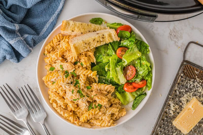 top-down view of the Italian Chicken Pasta served on a white plate with a salad.