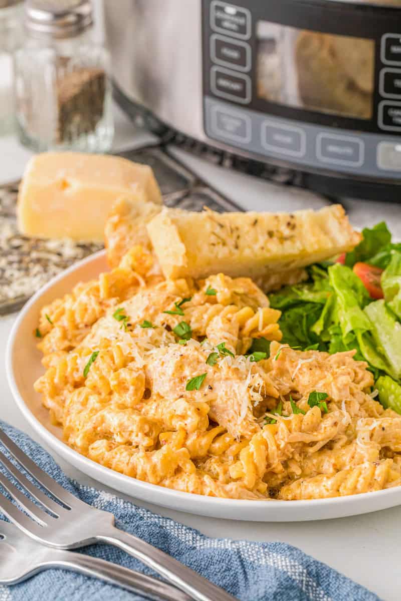 Italian Chicken Pasta served on a white plate with a salad.
