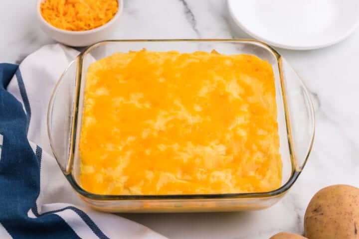 Cheesy Mashed Potatoes baked in a clear baking dish.