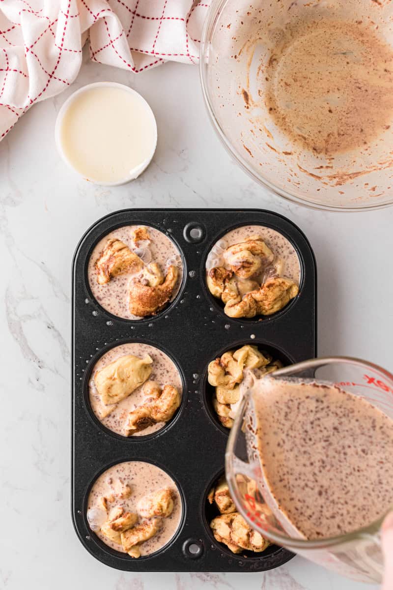 Pouring the egg mixture over the cinnamon roll muffins.