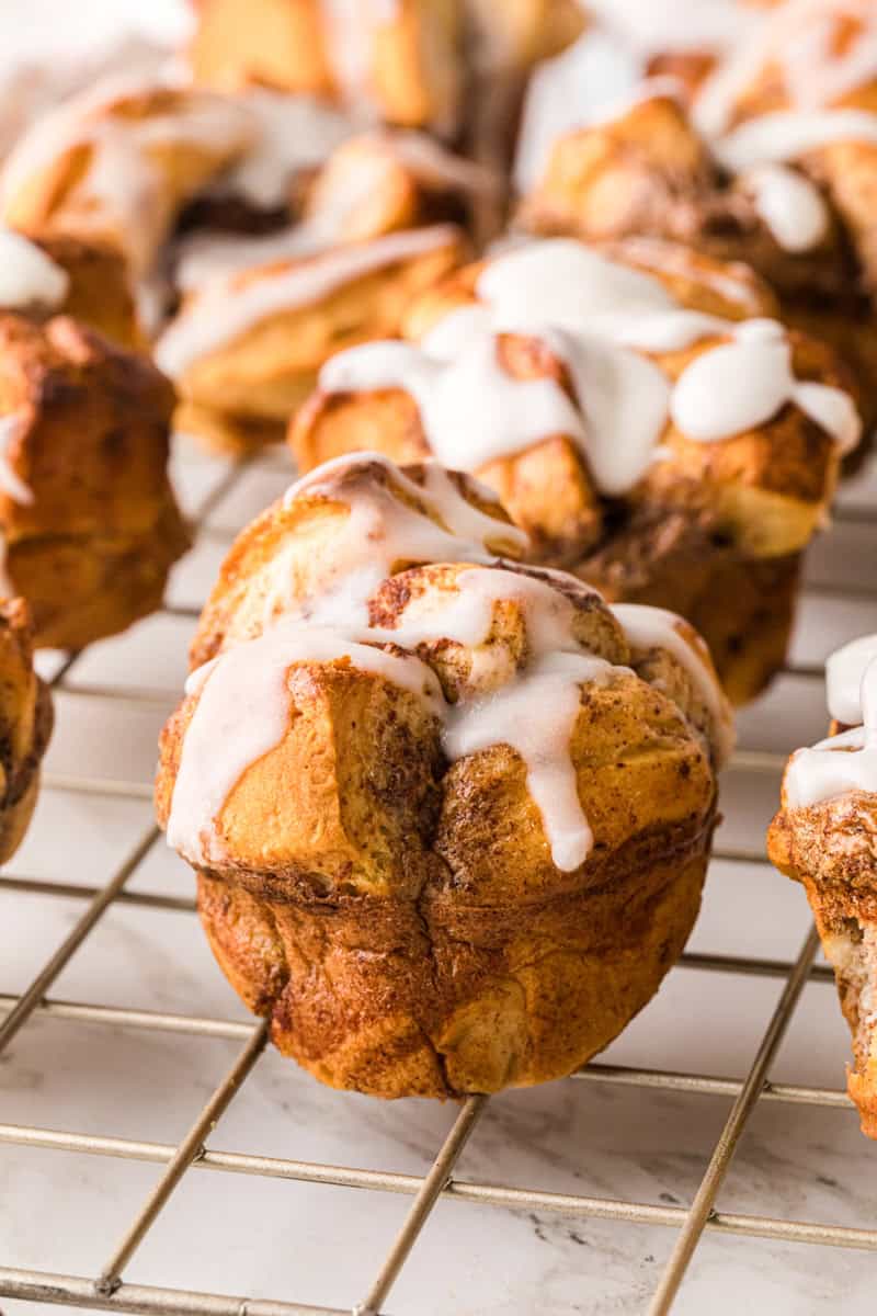 closeup if the cinnamon roll muffin on the wire rack.