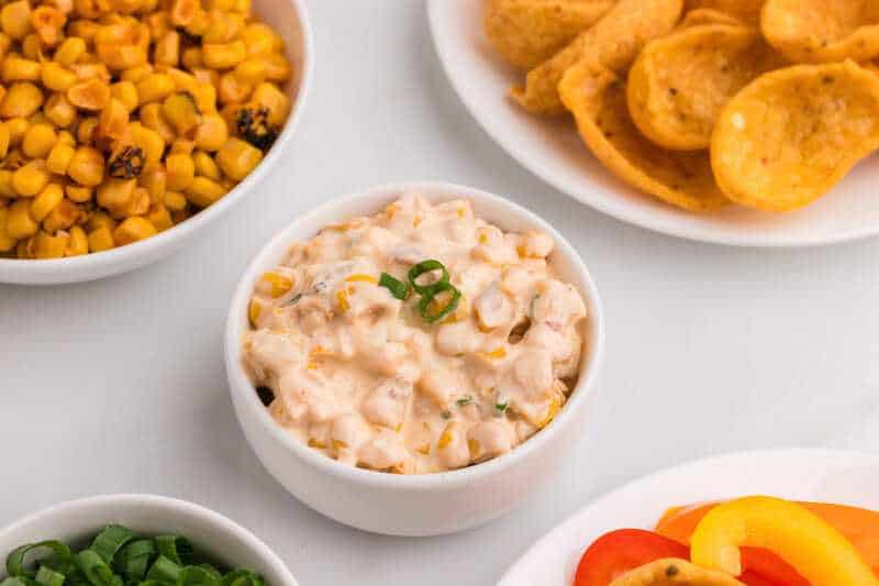 Crack Corn Dip served in a white bowl, with items to dip around it.