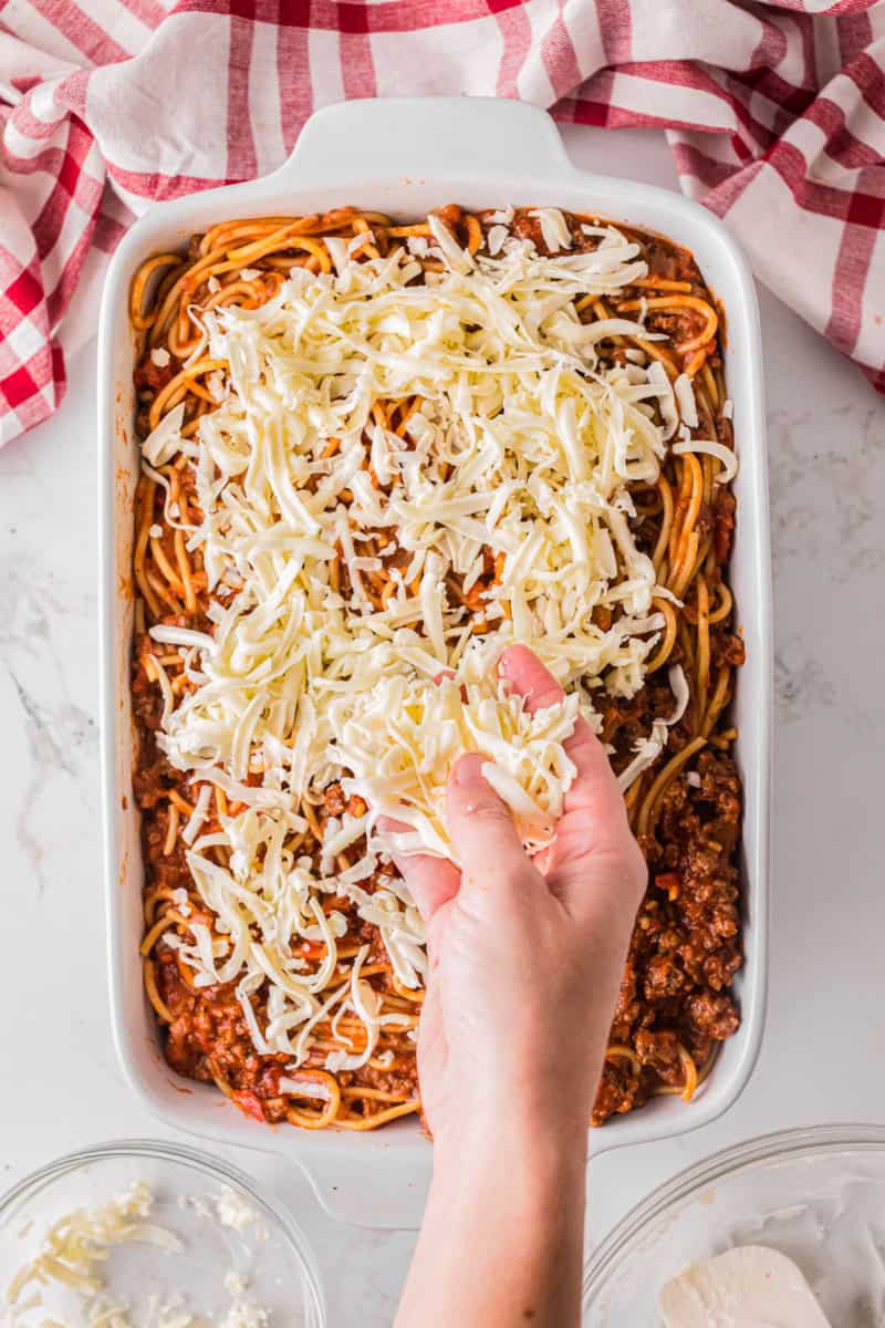 spreading mozzarella cheese on top of the million dollar spaghetti.