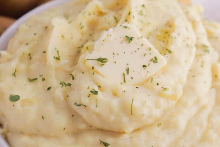 Slow Cooker Mashed Potatoes with a slab of butter on top.